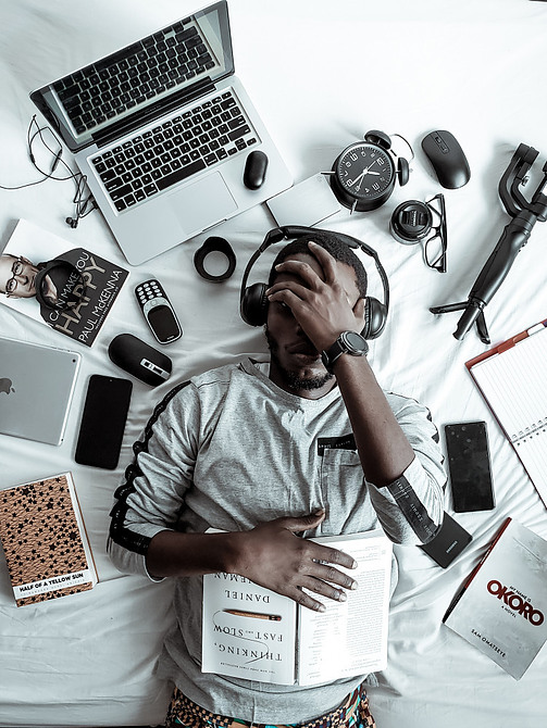 Man Laying on Bed with all Kinds of Tools to Start an Online Business
